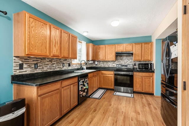 kitchen featuring tasteful backsplash, sink, black appliances, and light wood-type flooring