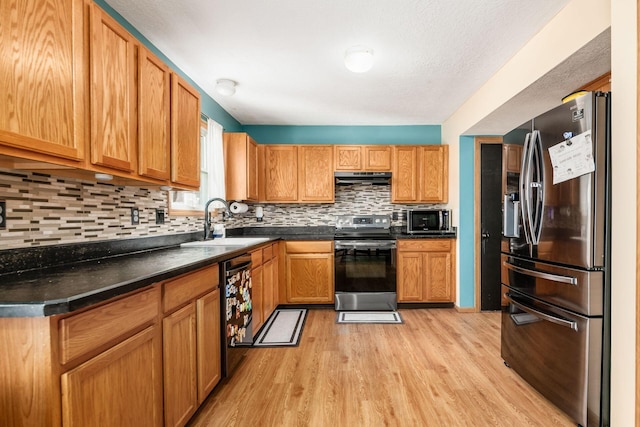 kitchen with stainless steel appliances, tasteful backsplash, sink, and light hardwood / wood-style flooring