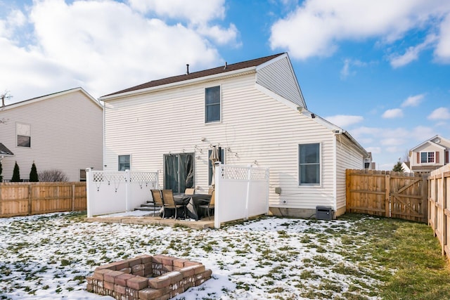 snow covered rear of property with a fire pit