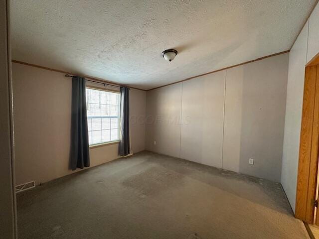 spare room with a textured ceiling and light carpet