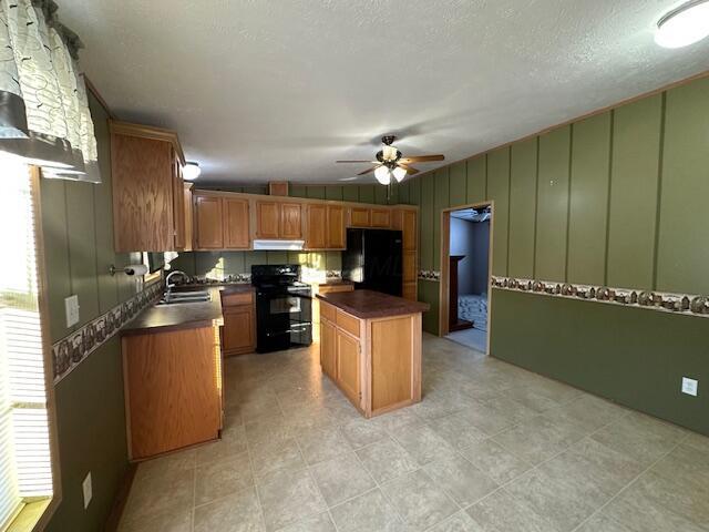 kitchen featuring ceiling fan, a kitchen island, black appliances, sink, and a textured ceiling