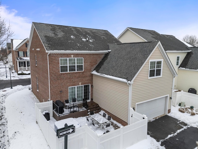 snow covered back of property featuring a garage