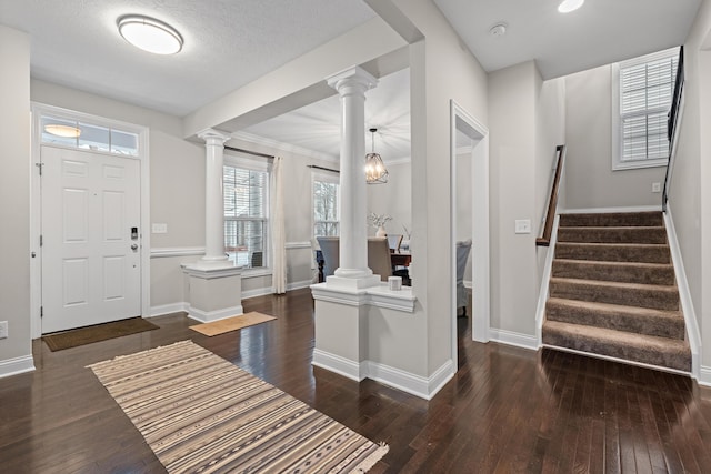 entryway featuring dark wood-type flooring, a textured ceiling, ornamental molding, and a chandelier