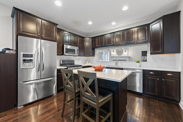 kitchen featuring dark brown cabinetry, appliances with stainless steel finishes, dark wood-type flooring, sink, and a breakfast bar