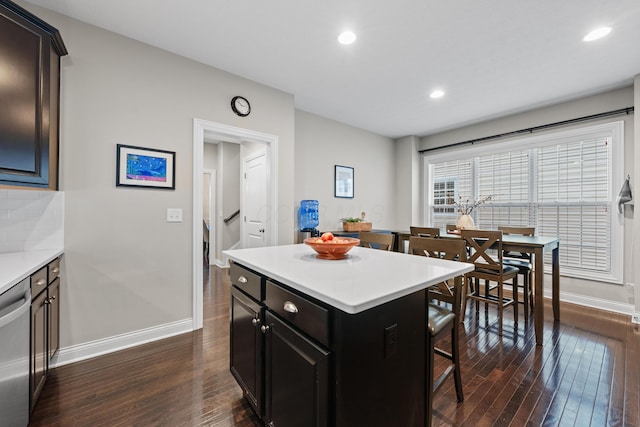 kitchen featuring decorative backsplash, a kitchen breakfast bar, dark hardwood / wood-style flooring, stainless steel dishwasher, and a center island