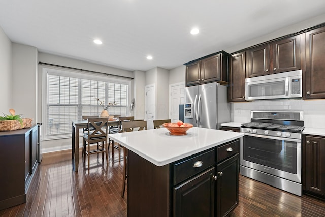 kitchen featuring a center island, a kitchen bar, decorative backsplash, stainless steel appliances, and dark hardwood / wood-style flooring