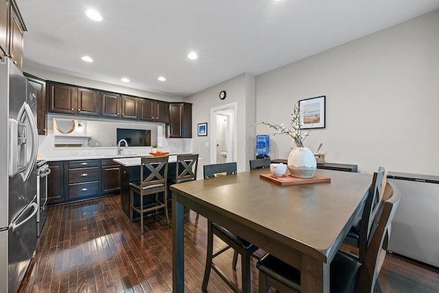 kitchen with dark hardwood / wood-style floors, a kitchen island, decorative backsplash, dark brown cabinetry, and appliances with stainless steel finishes