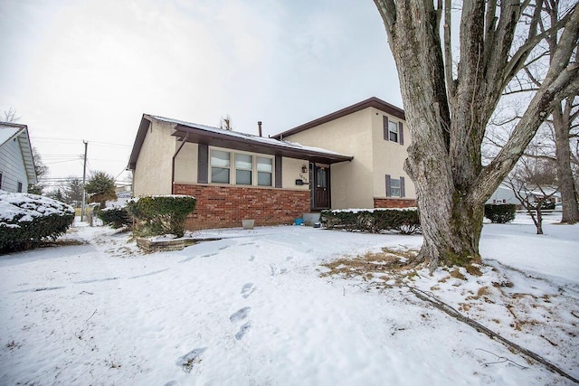 split level home featuring brick siding and stucco siding