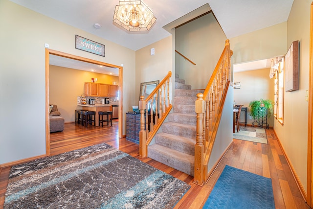 staircase with hardwood / wood-style flooring and an inviting chandelier