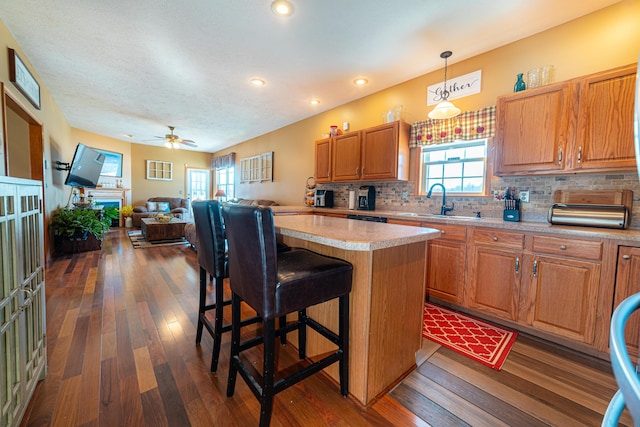 kitchen featuring a kitchen island, dark hardwood / wood-style flooring, a kitchen breakfast bar, hanging light fixtures, and decorative backsplash