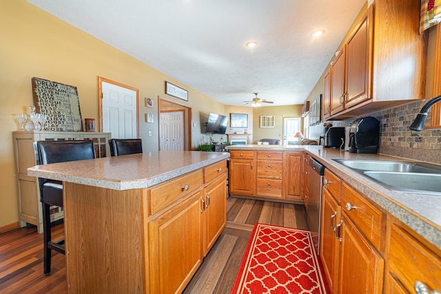 kitchen with dark hardwood / wood-style flooring, a kitchen island, sink, and a kitchen breakfast bar