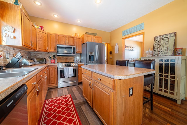 kitchen featuring appliances with stainless steel finishes, a kitchen breakfast bar, decorative backsplash, a center island, and dark wood-type flooring