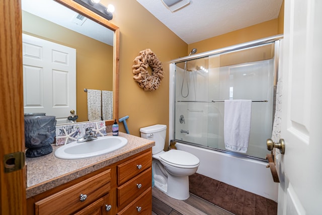 full bathroom with wood-type flooring, shower / bath combination with glass door, vanity, toilet, and a textured ceiling