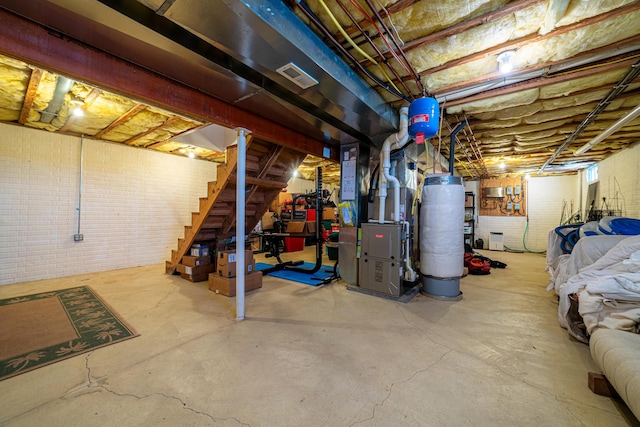 basement featuring heating unit, gas water heater, and brick wall