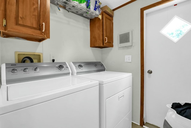 clothes washing area featuring cabinets and washing machine and clothes dryer