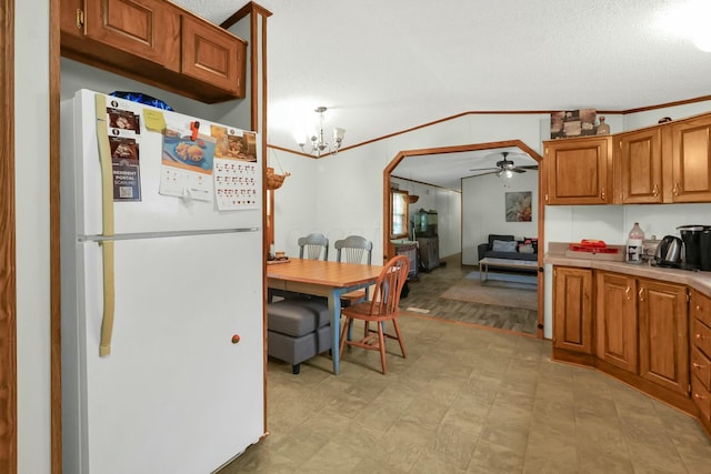 kitchen featuring hanging light fixtures, vaulted ceiling, white refrigerator, crown molding, and ceiling fan with notable chandelier