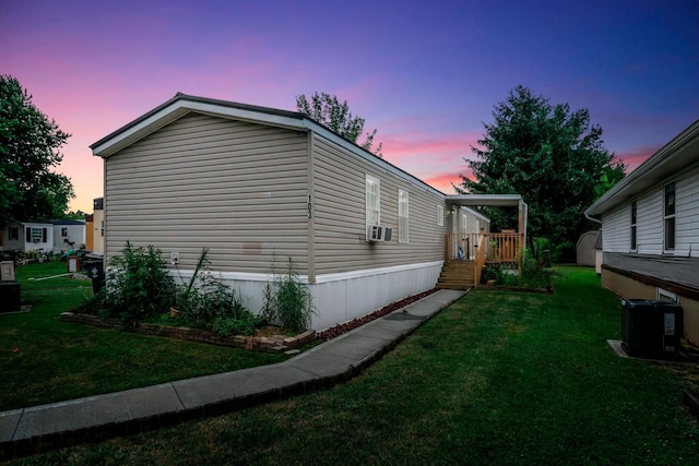 property exterior at dusk with cooling unit, a lawn, and central AC