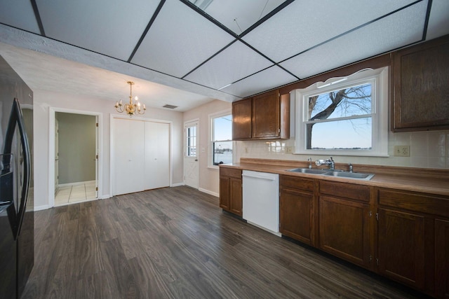 kitchen featuring tasteful backsplash, black refrigerator with ice dispenser, a paneled ceiling, dishwasher, and sink