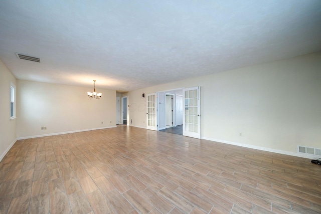 spare room with french doors and a chandelier