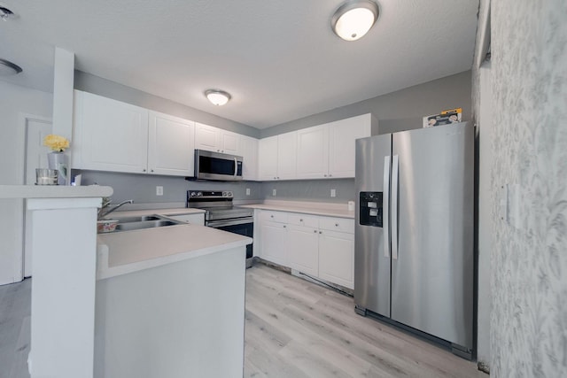 kitchen with light hardwood / wood-style floors, appliances with stainless steel finishes, a textured ceiling, white cabinets, and sink