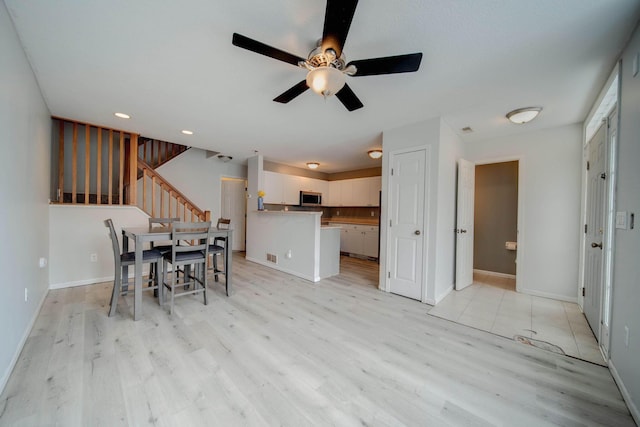 unfurnished dining area featuring light wood-type flooring and ceiling fan