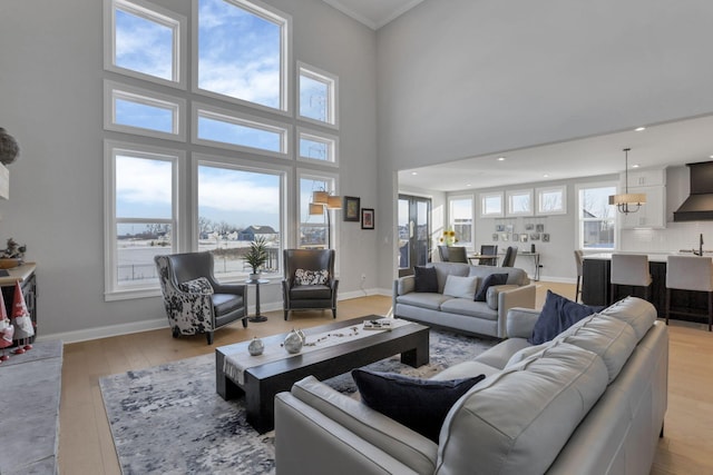 living room featuring a healthy amount of sunlight, light wood-type flooring, and a towering ceiling