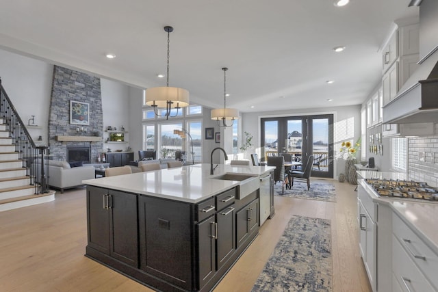 kitchen featuring white cabinetry, pendant lighting, an island with sink, and stainless steel gas cooktop