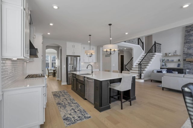 kitchen featuring sink, white cabinetry, hanging light fixtures, an island with sink, and stainless steel appliances