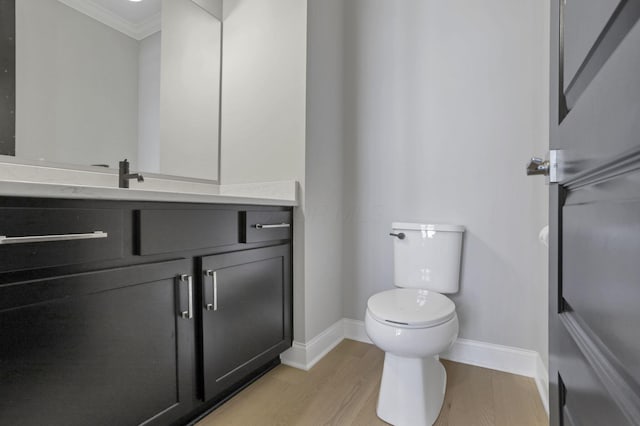 bathroom with vanity, wood-type flooring, ornamental molding, and toilet