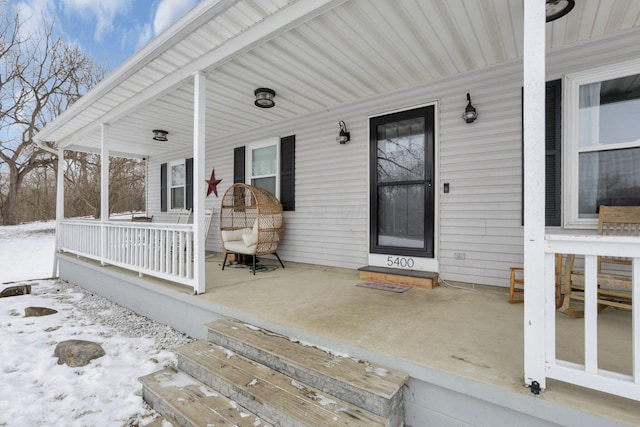 snow covered property entrance with covered porch