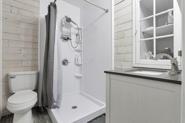 bathroom with hardwood / wood-style floors, vanity, curtained shower, toilet, and wood walls