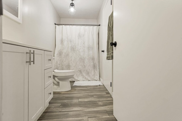 bathroom with hardwood / wood-style flooring, vanity, toilet, and walk in shower