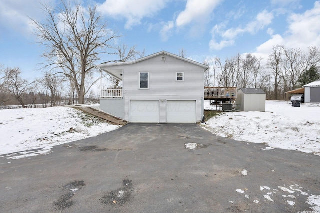 snow covered property featuring a garage and a wooden deck