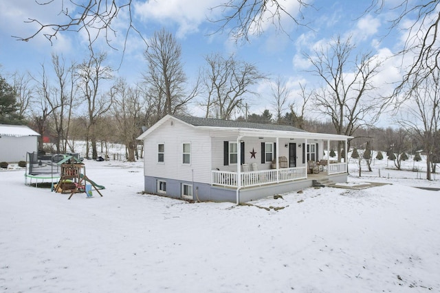 view of front facade featuring a trampoline, a playground, and covered porch