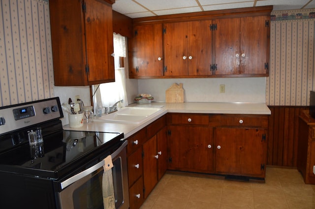 kitchen with stainless steel electric range oven, sink, and wood walls