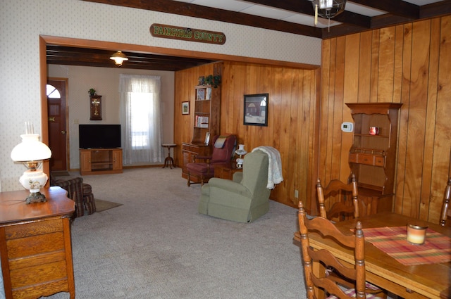 carpeted living room featuring beam ceiling and wooden walls