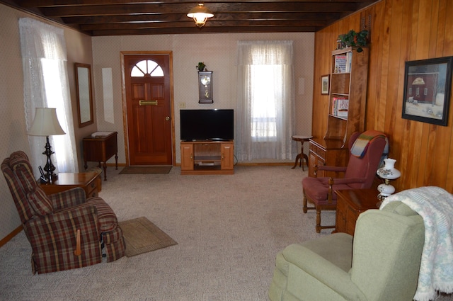 living room featuring light colored carpet, wood walls, and beamed ceiling