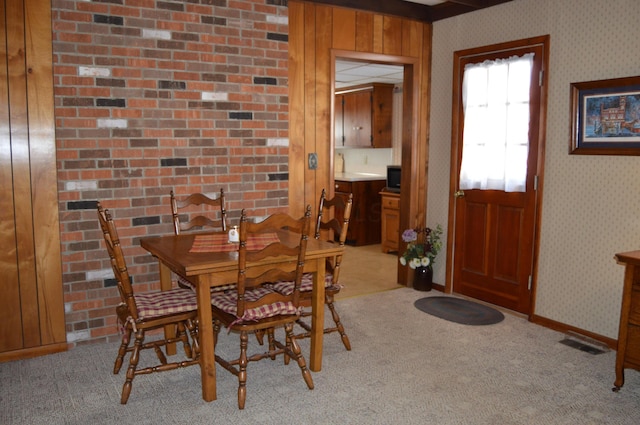 dining room featuring wood walls and light carpet