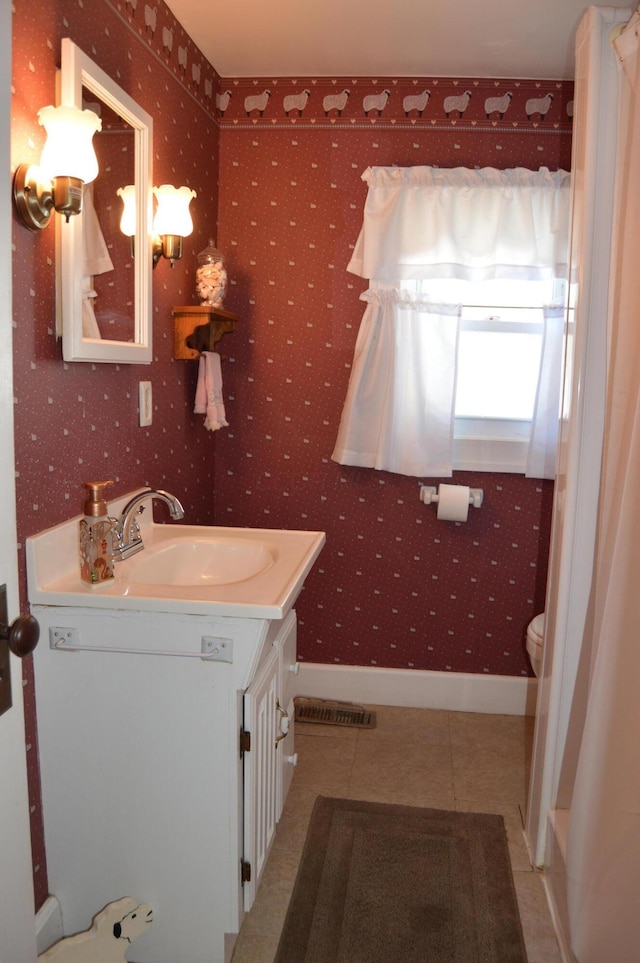 bathroom with toilet, vanity, and tile patterned flooring