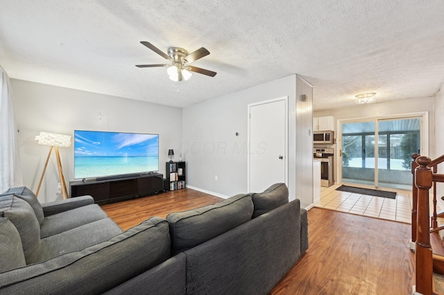 living room with light hardwood / wood-style floors, a textured ceiling, and ceiling fan