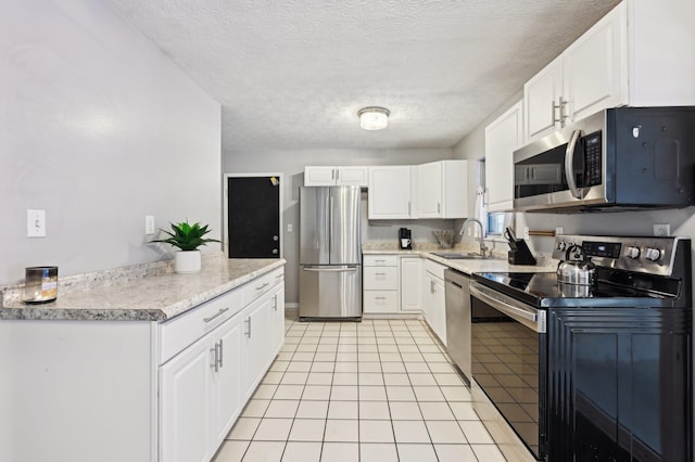 kitchen with a textured ceiling, white cabinets, appliances with stainless steel finishes, sink, and light tile patterned floors