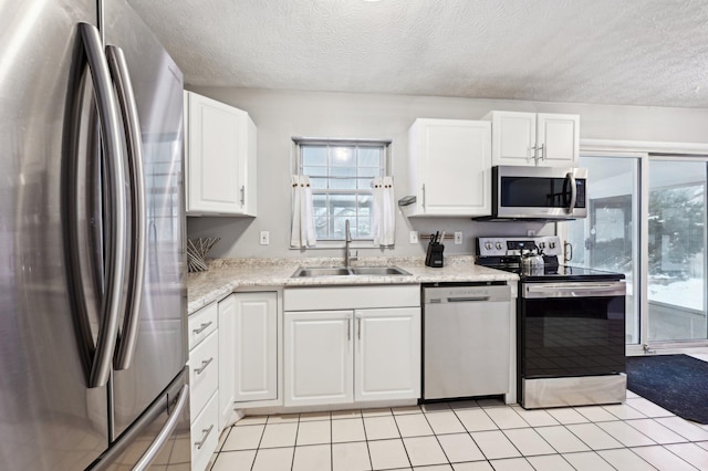 kitchen with appliances with stainless steel finishes, sink, white cabinetry, and a textured ceiling