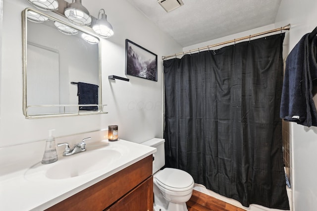 bathroom with curtained shower, a textured ceiling, wood-type flooring, vanity, and toilet