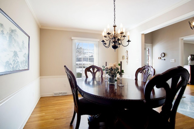 dining space featuring baseboards, light wood-type flooring, visible vents, and crown molding