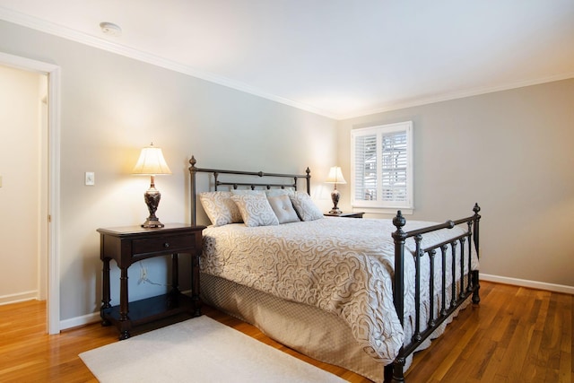 bedroom featuring baseboards, wood finished floors, and ornamental molding