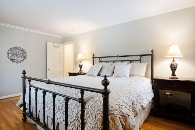 bedroom with crown molding, baseboards, and wood finished floors