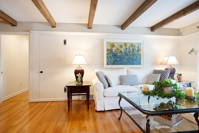 living area with light wood-style floors, beam ceiling, and visible vents