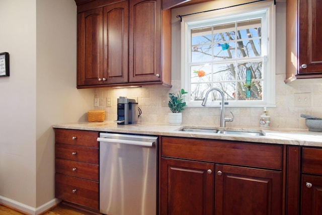 kitchen with light stone countertops, a sink, baseboards, decorative backsplash, and dishwasher