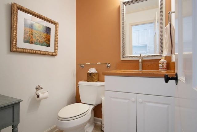 bathroom featuring baseboards, vanity, and toilet