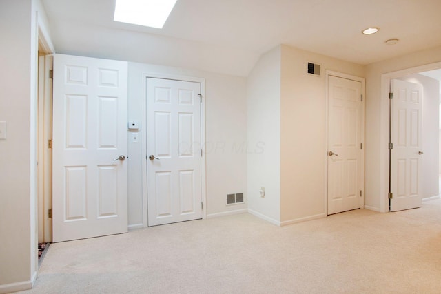 unfurnished bedroom featuring light carpet, a skylight, and visible vents